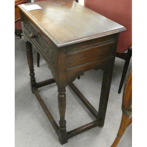 22 - An early 20thC Jacobean style, oak single drawer side table, raised on turned and block legs  3... 