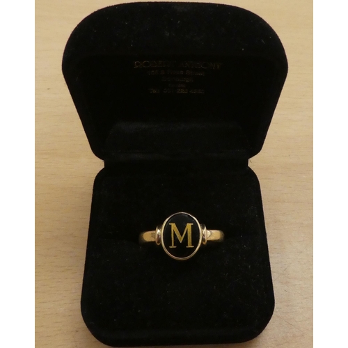 221 - A yellow metal ring, set with a black stone with the letter M  