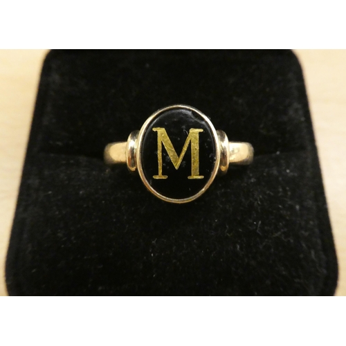 221 - A yellow metal ring, set with a black stone with the letter M  