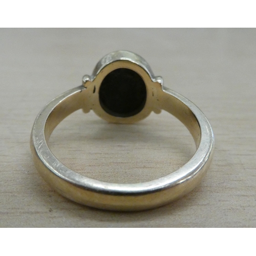 221 - A yellow metal ring, set with a black stone with the letter M  