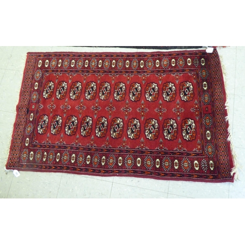 262 - Rugs: to include a Bokhara with elephant foot motifs, on a red ground  50