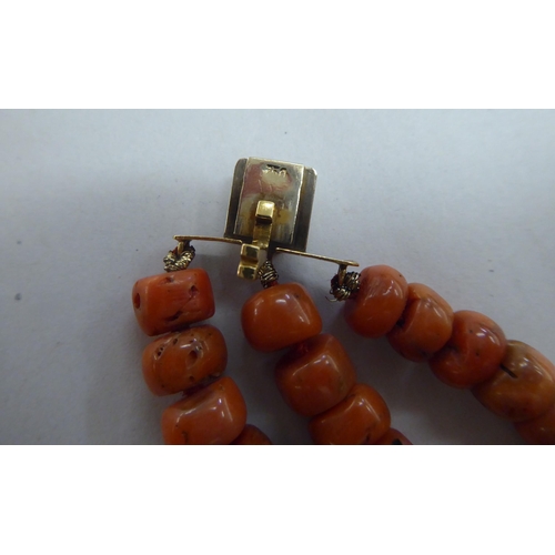 306 - A triple row coral string necklace with an 18ct gold and three diamond set clasp