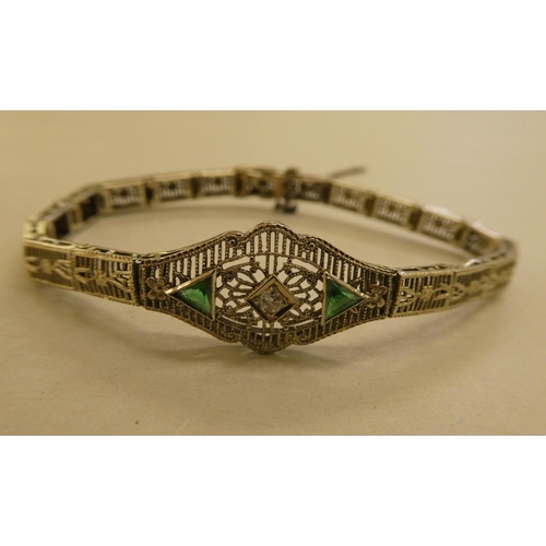 317 - A white metal fine wire hinged bracelet, set with a central diamond and green stones  stamped 14k