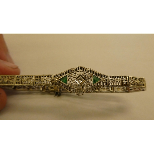 317 - A white metal fine wire hinged bracelet, set with a central diamond and green stones  stamped 14k