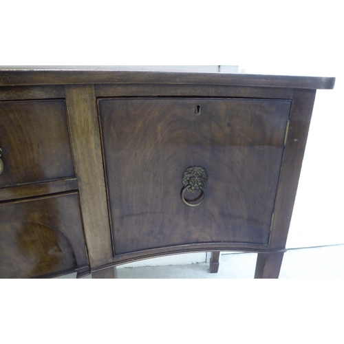 42 - An early 20thC Georgian design mahogany serpentine front serving sideboard with two central drawers,... 