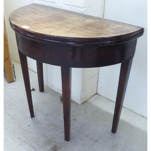 51 - A George III mahogany demi-lune tea table, the hinged top raised on square, tapered legs  28