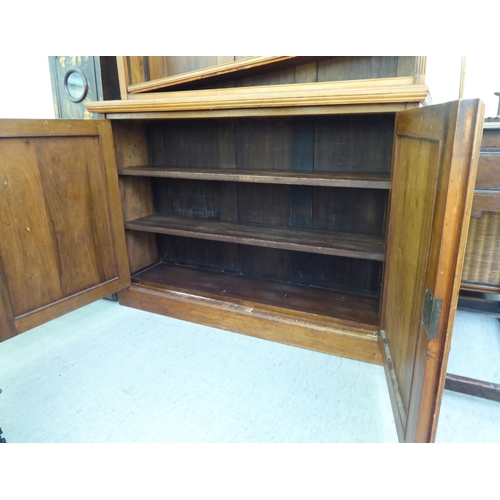 55 - An Edwardian mahogany cabinet bookcase, the superstructure with three open shelves, over a pair of p... 