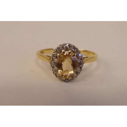 80 - An 18ct bi-coloured gold ring, set with a central yellow stone, surrounded by small diamonds