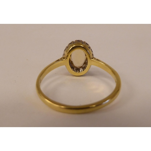 80 - An 18ct bi-coloured gold ring, set with a central yellow stone, surrounded by small diamonds