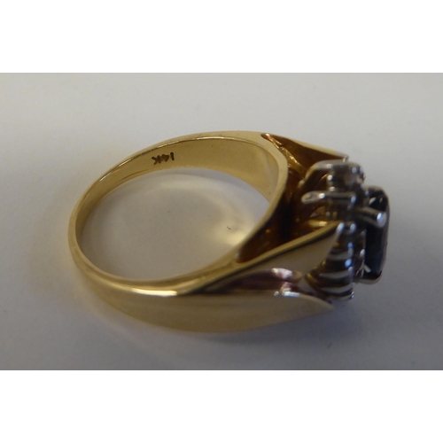 90 - A 14ct gold ring, set with a sapphire and diamond, surrounded by small claw set diamonds