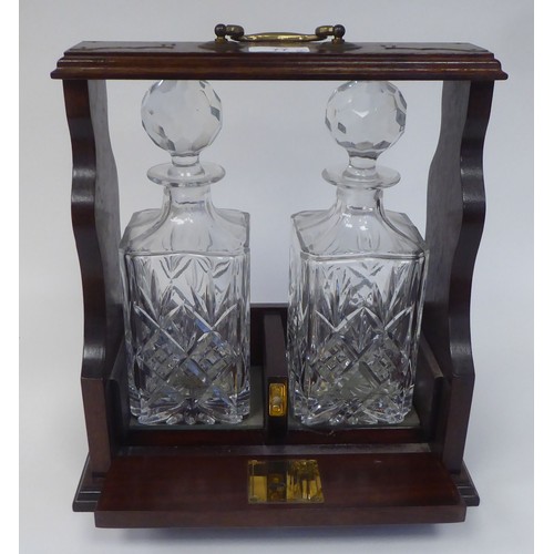 77 - A modern oak tantalus, accompanied by two glass decanters  12.5