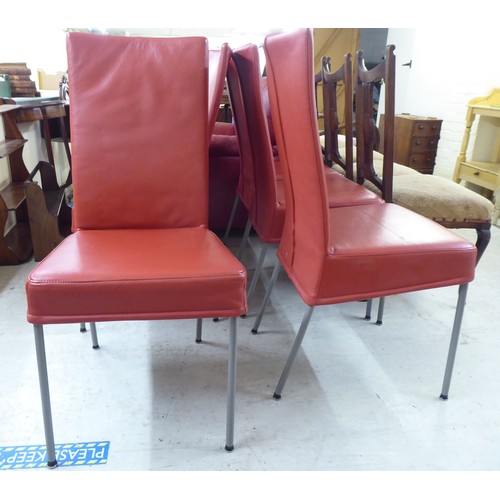 239 - A set of six modern red faux hide upholstered dining chairs, raised on splayed metal legs