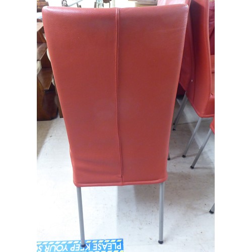 239 - A set of six modern red faux hide upholstered dining chairs, raised on splayed metal legs