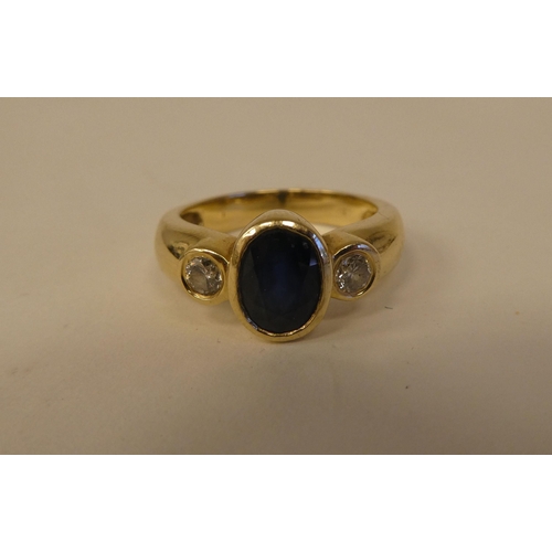 10 - A yellow metal ring, set with a blue stone, flanked by two diamonds