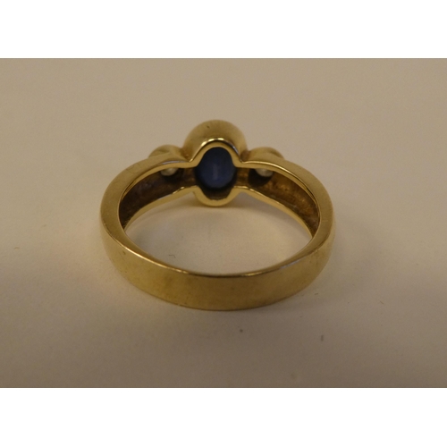 10 - A yellow metal ring, set with a blue stone, flanked by two diamonds