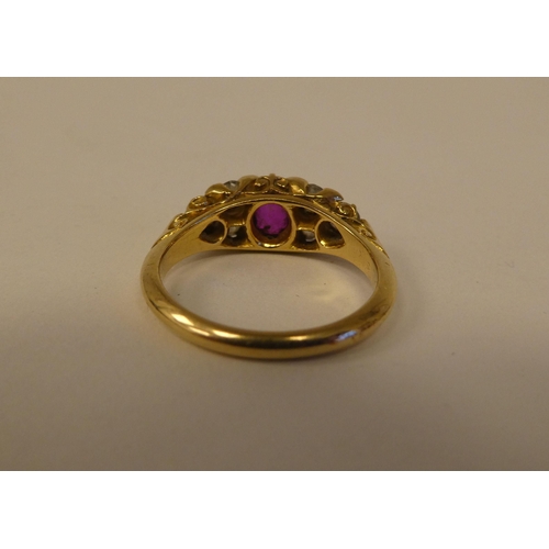 11 - An 18ct gold ring, set with a central pink/red stone, flanked by six diamonds