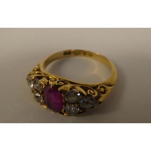 11 - An 18ct gold ring, set with a central pink/red stone, flanked by six diamonds