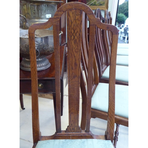 18 - A set of six early 20thC oak framed dining chairs, the fabric upholstered drop-in seats raised on tu... 