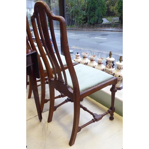 18 - A set of six early 20thC oak framed dining chairs, the fabric upholstered drop-in seats raised on tu... 