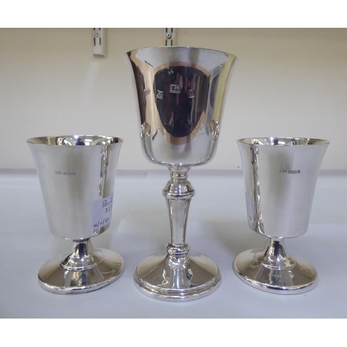 323 - A pair of modern silver goblets, the inverted bell shaped bowls on domed pedestals; and another of s... 