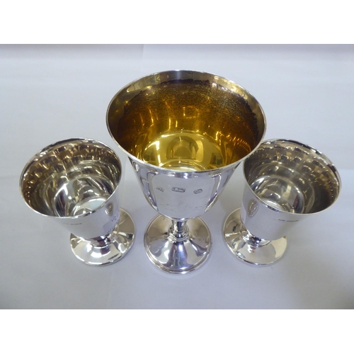 323 - A pair of modern silver goblets, the inverted bell shaped bowls on domed pedestals; and another of s... 