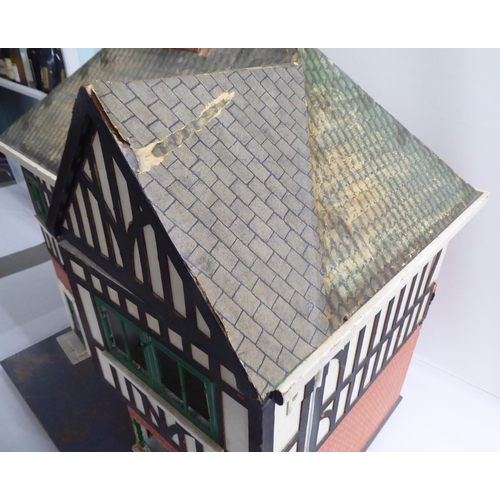 47 - A 20thC scratch built doll's house, fashioned as a faux brick Tudor inspired home with front hinged ... 