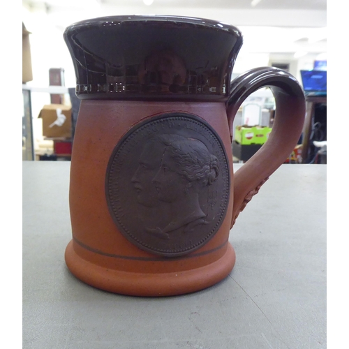 124 - A David Birch Pulman Pottery terracotta mug with a moulded loop handle and Royal Commemorative medal... 