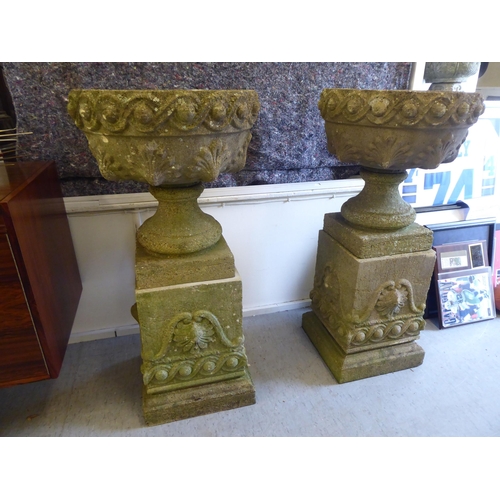 149 - A pair of composition stone garden urns, each on a plinth  40