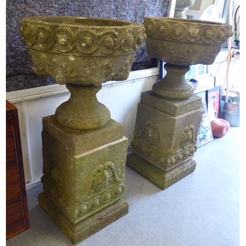 149 - A pair of composition stone garden urns, each on a plinth  40