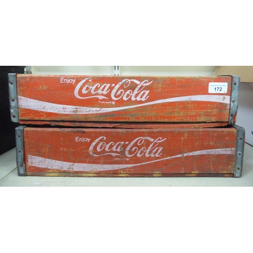 172 - A pair of red stained pine Coco-Cola bottle trays with iron re-enforcement and twenty-four apertures... 