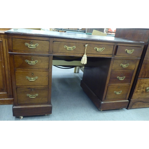 185 - An early 20thC mahogany nine drawer, twin pedestal desk, the top set with a green hide scriber, on a... 