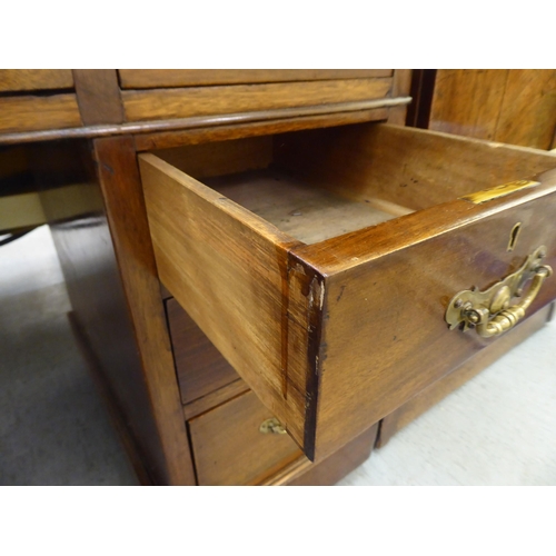 185 - An early 20thC mahogany nine drawer, twin pedestal desk, the top set with a green hide scriber, on a... 