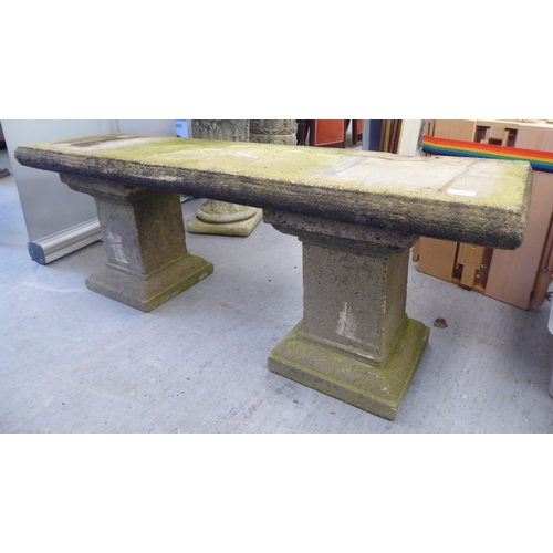 203 - A three part composition stone garden bench, raised on block pedestals  52