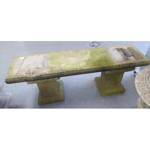 203 - A three part composition stone garden bench, raised on block pedestals  52