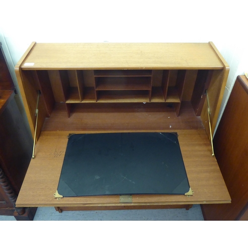 276 - A modern teak bureau, the fall flap enclosing a blotter and pigeon holes, over two drawers and two d... 