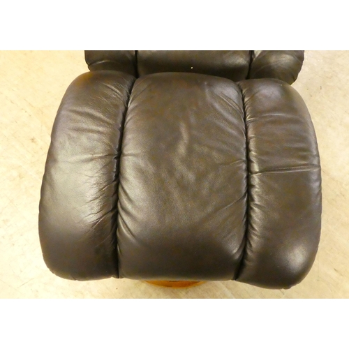 44 - A modern rotating easy chair, upholstered in simulated hide; and a matching footstool