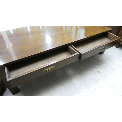 50 - A modern mahogany finished coffee table with two drawers and brass capped corners, raised on block l... 