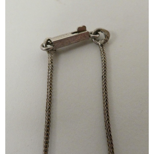 81 - A white metal pendant, set with a teardrop cut garnet, on a white metal chain  stamped 800