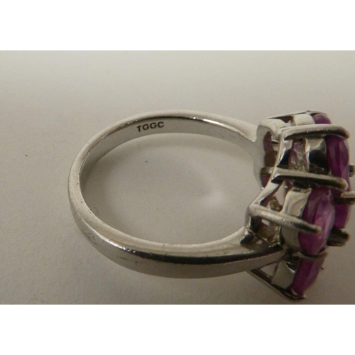 91 - A white metal cluster ring, set with seven pink sapphires  stamped 925