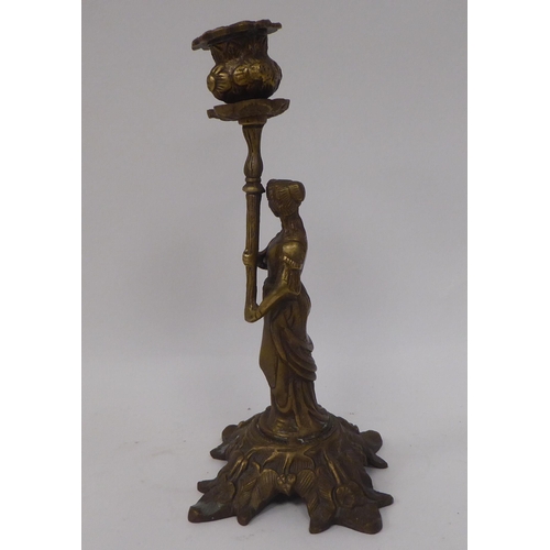 11 - A pair of cast brass candlesticks, respectively featuring a man and a woman wearing 18thC costume, e... 