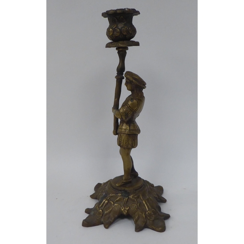 11 - A pair of cast brass candlesticks, respectively featuring a man and a woman wearing 18thC costume, e... 