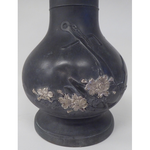 115 - A 19thC Japanese Meiji period bronze bottle vase with a narrow neck and flared rim, decorated in par... 