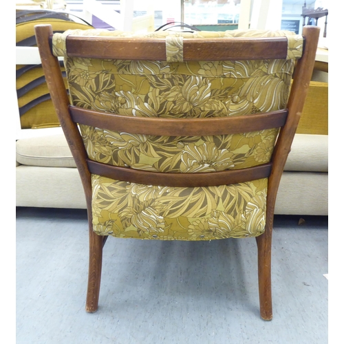 166 - A vintage Parker Knoll, stained beech framed fireside armchair, raised on turned legs and stretchers