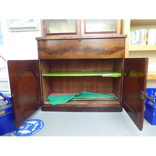 169 - A mid Victorian mahogany cabinet bookcase with a straight cornice, over a pair of glazed doors, encl... 