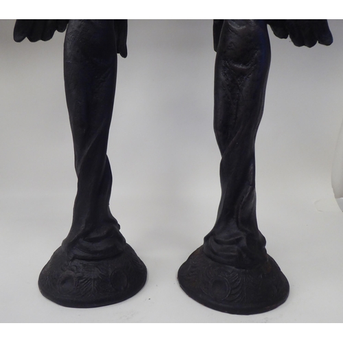 17 - A pair of Victorian style black painted and decoratively cast iron figural candlesticks, each depict... 