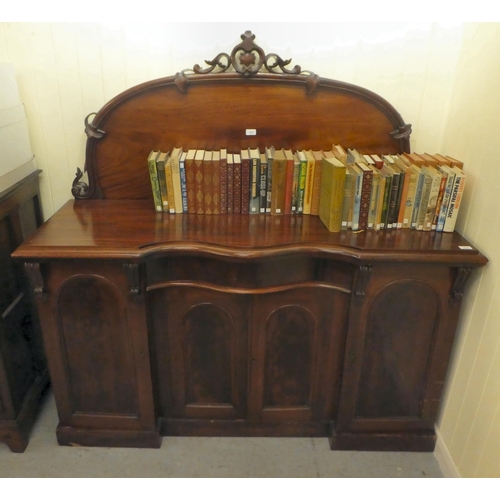 172 - A mid Victorian mahogany inverted breakfront sideboard with a carved, D-shaped upstand, over a centr... 