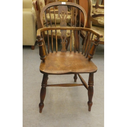 177 - A mid 19thC oak and elm framed, low hoop, spindled back Windsor arm chair with a pierced splat, the ... 