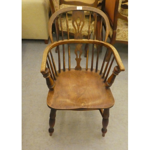 177 - A mid 19thC oak and elm framed, low hoop, spindled back Windsor arm chair with a pierced splat, the ... 