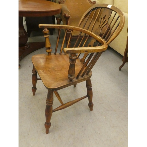 177 - A mid 19thC oak and elm framed, low hoop, spindled back Windsor arm chair with a pierced splat, the ... 