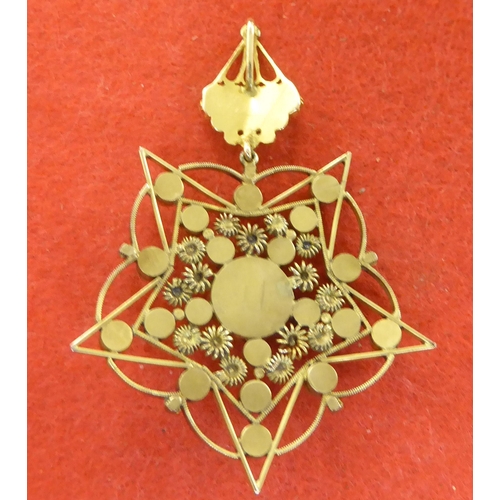 227 - A yellow metal star design pendant, set with garnets and seed pearls